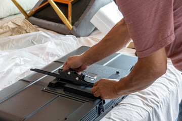 man installing the wall base for the television, it is a smart tv, adjusting with screwdriver