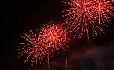Fogo de artifício de cor vermelha a rebentar em céu aberto