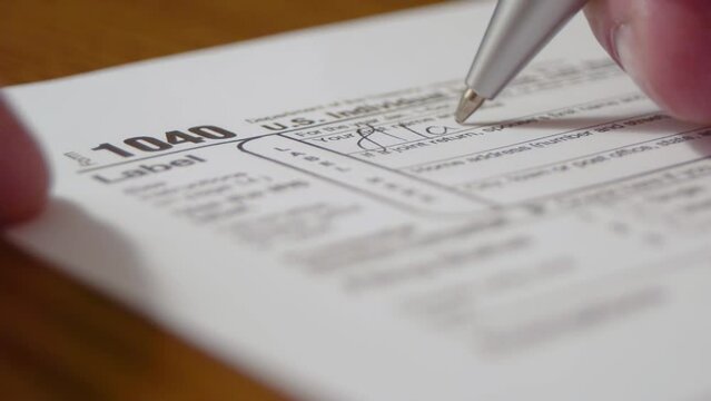 Man fills out 1040 US income tax return IRS form by hand.