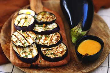Grilled eggplant on a wooden board with honey mustard sauce.