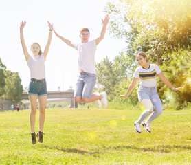 Happy teenagers jumping on the green lawn on spring