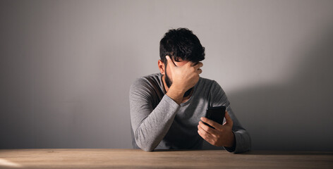 Obraz premium A man sits in front of a table covering his face with his hand