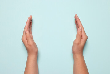 Woman holding on light blue background, closeup of hands. Space for text