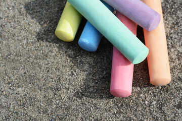 Many colorful chalk sticks on asphalt, above view. Space for text