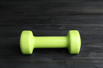 Light green vinyl dumbbell on black wooden table