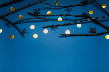 Black branches and spiders on blue background, above view with space for text. Halloween celebration