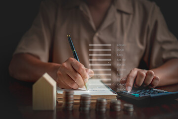 Businessman taking notes  and using calculator to calculate, Stacking coins, graph, wooden house on table. plan revenue and expenses, target success growth, finance profit planning concept.