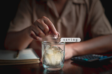 Businessman holding coins putting in jar, calculator and notbook,pen  on table. plan revenue and expenses, target success growth, finance profit planning concept.