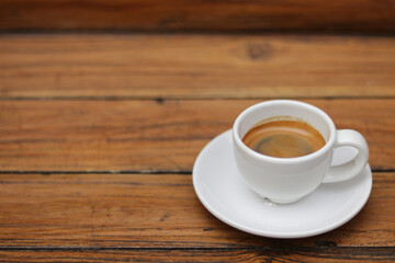 Espresso coffee in white ceramic cup on wooden table background.  Espresso can be made with a wide variety of coffee beans and roast degrees.