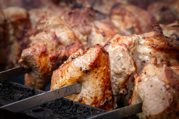 Meat shashlik, also known as shish kebab, is grilled on a charcoal grill. Slices of meat on steel skewers close-up. Delicious traditional Caucasian meat dish