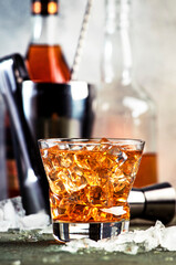 Godfather cocktail with scotch whiskey, amaretto liqueur and ice. Gray bar counter background, bar tools, copy space