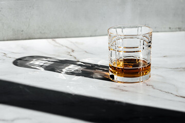 whiskey glass drink with sun light and shadow on a marble table 