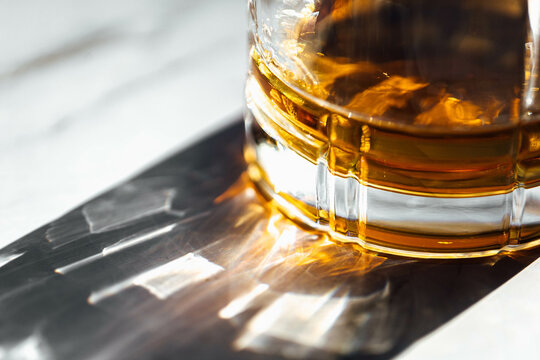 whiskey glass detail bottom view with sun light on a marble table 