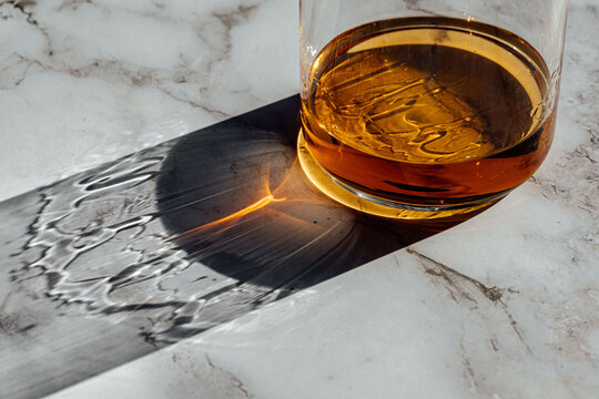 whiskey glass detail bottom view with sun light on a marble table 