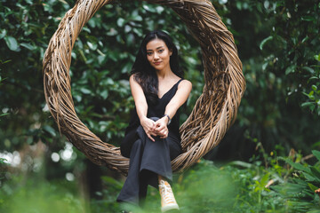 fashion portrait of sexy cute woman person, beautiful Asian model girl wearing black dress in nature garden , attractive happy lady at park outdoor, female pretty having relax and happy lifestyle
