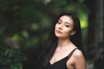 fashion portrait of sexy cute woman person, beautiful Asian model girl wearing black dress in nature garden , attractive happy lady at park outdoor, female pretty having relax and happy lifestyle