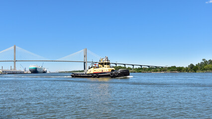 A tugboat plies the water of the Savannah River along the waterfront of the city.