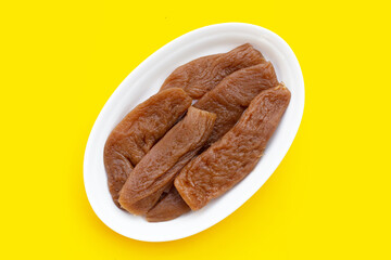 Preserved turnip (radish) in plate on yellow background.