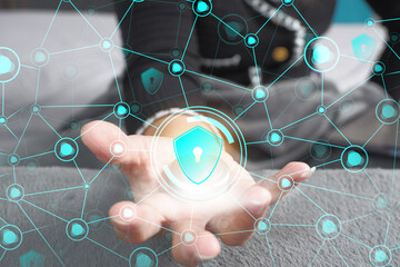 Close-up of a woman's hand holding a security shield icon hologram. Data protection concept and technology