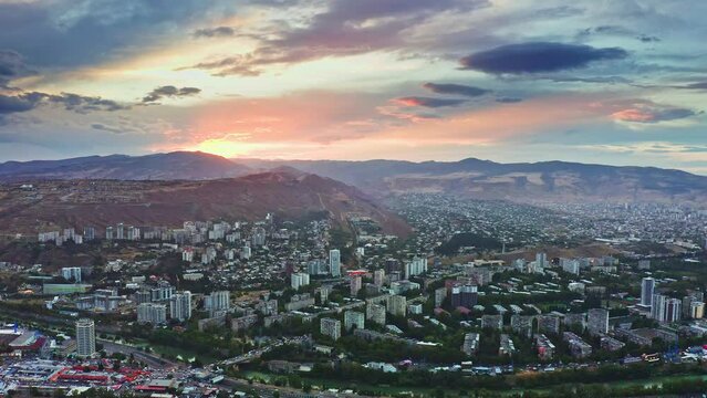 Aerial view of Tbilisi urban skyline under sunset sky