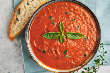 Top view of fresh homemade tomato basil soup with fresh herbs and slice of focaccia bread