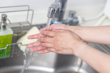 Fototapeta na wymiar キッチンのシンクで手を洗う女性の手元