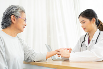 Fototapeta premium Doctor taking the pulse of her senior patient.