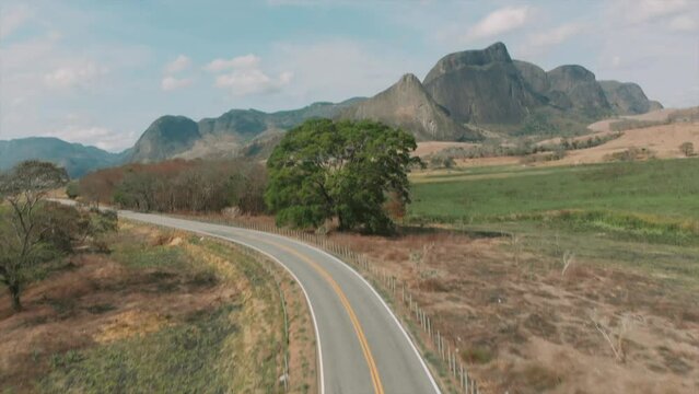 CURVA NA ESTRADA, UMA ARVORE E A MONTANHA AO FUNDO. BAIXO GUANDU - ESPIRITO SANTO