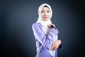 Portrait of a beautiful female model wearing hijab, a lifestyle apparel for Muslim women isolated on brown background. Idul Fitri and hijab fashion concept. Isolated on dark background