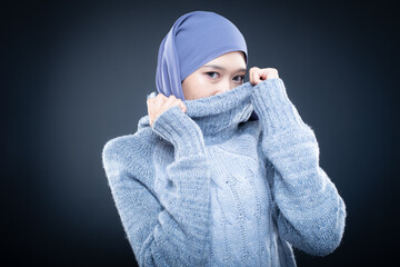 Portrait of a beautiful female model wearing hijab, a lifestyle apparel for Muslim women isolated on brown background. Idul Fitri and hijab fashion concept. Isolated on dark background
