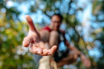 Young hiker man hold someone hand help to climb up