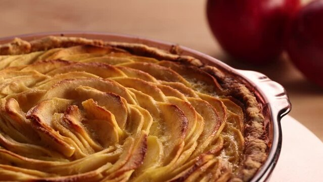 Slider shot of rotating golden apple pie on rustic wooden table, traditional food of the fall season. Thanksgiving recipes