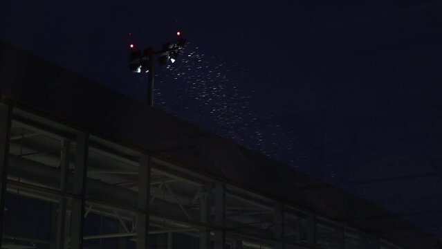 Snow is flying in front of the light at night. 