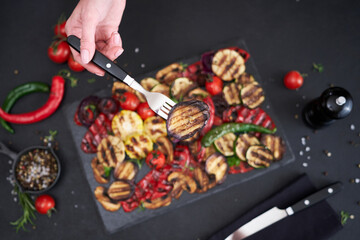 Grilled vegetables mix on a stone serving board - zucchini eggplant onions corn mushroom tomato