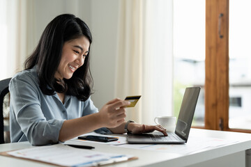 Asian business woman holding credit card and typing on laptop for online shopping and payment makes a purchase on the Internet, Online payment, Business financial and technology concept