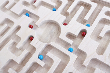Blue and red balls searching for solutions to the center of a wooden maze