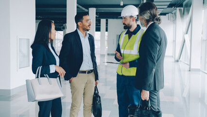 Multi-ethnic group of investors are shaking hands and talking to builder in uniform discussing construction project. Business and real estate concept. - 536220246