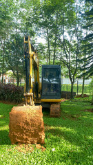 Yellow excavator digs a trench in a residential park