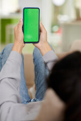 Blank green screen of smartphone in hands of young woman in casualwear