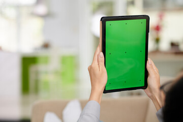 Selective focus on hands of woman and tablet with blank green screen
