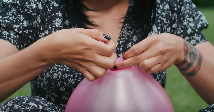 a happy woman inflates balloons and they burst, showing that everything is wrong with condoms and they are torn.
