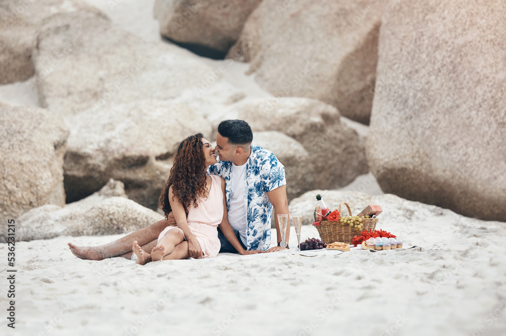 Wall mural couple, beach and love on picnic, kiss and happy together on sand by rock. man, woman and smile with