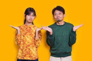 shock and surprise young asian  couple feel disappointed isolated on yellow background
