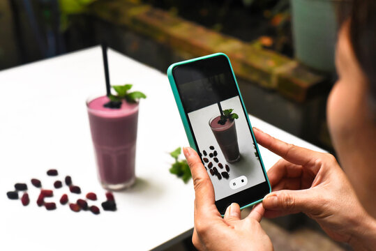 A woman taking picture of mulberry smoothie for advertisement 