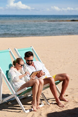 Couple using tablet pc on the beach