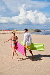 Couple with swimming mattresses on the beach