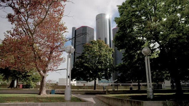 Renaissance Center in Detroit, Michigan with gimbal video walking forward by trees in slow motion.
