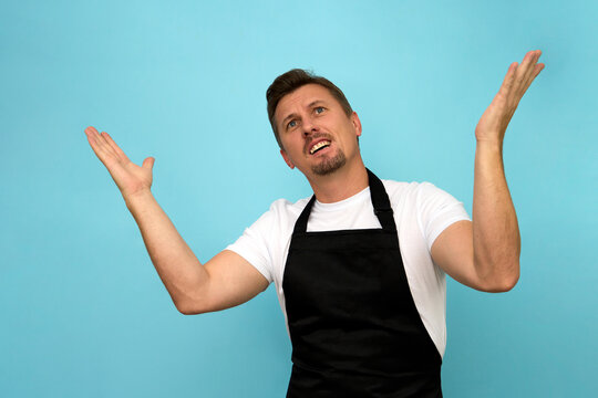 Young Barista In Black Apron And White T-shirt On Blue Background