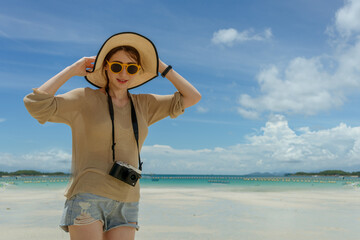 portait of woman wearing sun hat sungrasses and have camera standing on the beach with sunny day
