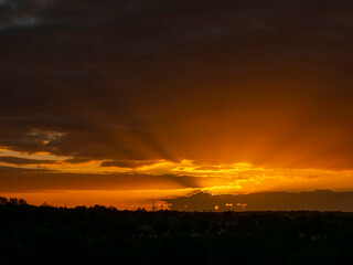 Dramatic sunset nature scene. Warm orange color sky with sun rays and flare. Stunning nature scene at dusk.